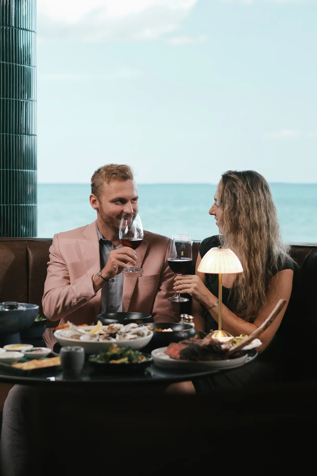 Two people dining with Sanur's ocean in the background